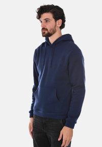 Felpa con cappuccio di colore blu navy, realizzata in cotone, con tasca a marsupio, cappuccio regolabile tramite cordino e polsini a costina. Design semplice, colore uniforme, texture morbida.
