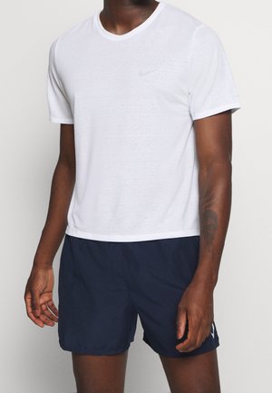 Camiseta blanca de Nike con mangas cortas, cuello redondo y tejido texturizado. Se combina con pantalones cortos azul marino que presentan un detalle de logotipo blanco.
