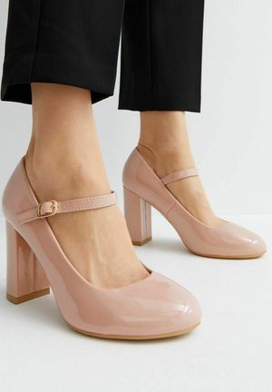 Roze gepatenteerde leren hakken met een ronde neus en een gesp op de bovenkant. De blokhak is ongeveer 5 cm hoog.