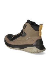 Wasserdichte Wanderschuhe mit schwarzem Obermaterial, Akzenten aus braunem Wildleder, strukturiertem Gummisohle und einer gelben Zuglasche an der Ferse.