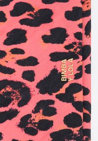 Lauka ar leopardu rakstu spilgtā rozā krāsā ar melniem plankumiem, ar zelta logotipu "BIMBA Y LOLA", kas labi redzams.