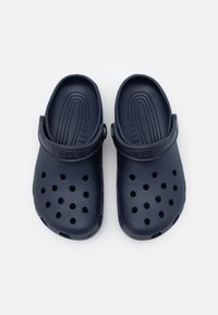 Zoccoli blu navy con una texture liscia e fori di ventilazione; dotati di cinturino posteriore e plantare testurizzato per il comfort.