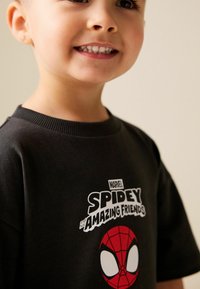Schwarzes Baumwoll-T-Shirt mit weißem Aufdruck "MARVEL SPIDEY and his AMAZING FRIENDS" und einer roten Spider-Man-Gesichtsillustration auf der Vorderseite.