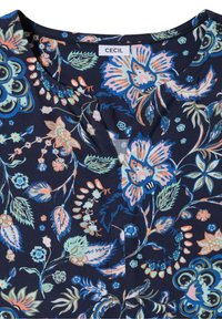 Blouse bleu foncé avec imprimé floral multicolore aux tons pastel et un col rond avec une petite fente au centre devant.