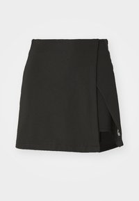 Jupe mini noire en tissu texturé, avec un ourlet asymétrique et une fente sur le côté. Design simple sans accessoires ni motifs visibles.