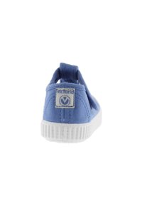 Scarpa slip-on in tela blu con suola in gomma bianca. Presenta una linguetta sul retro per una facile calzata e un'etichetta logo sul tallone. Design in tessuto testurizzato.