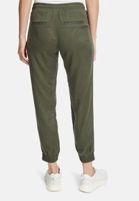Olive green joggers with an elastic waistband and cuffed ankles. Two back pockets with straight seams, made from soft, lightweight fabric.