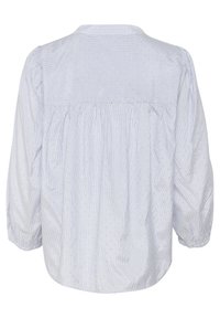 Blusa azzurra chiara con retro arricciato, caratterizzata da sottili pois bianchi e una texture a righe. Maniche a palloncino con polsini elasticizzati.