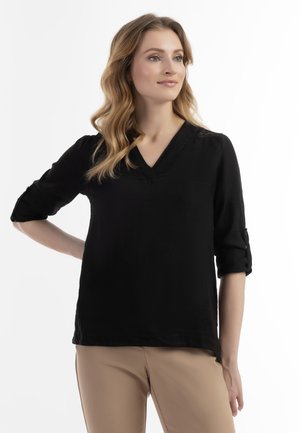 Zwarte, lange mouwen V-halsblouse van lichtgewicht stof, met opgerolde mouwen en een ontspannen pasvorm. Glad textuur, geen zichtbare patronen.