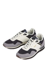 Sneakers featuring a blend of dark grey, cream, and light grey materials. Classic lace-up design with a textured rubber sole and minimal branding.