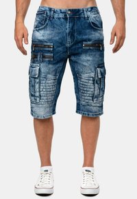Shorts in denim azzurro chiaro, dotati di molteplici tasche con zip, texture a coste, orli arrotolati e dettagli di cucitura a contrasto.
