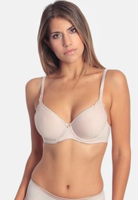 Nude underwire bra with floral lace accents, smooth fabric, adjustable straps, and a decorative front clasp.