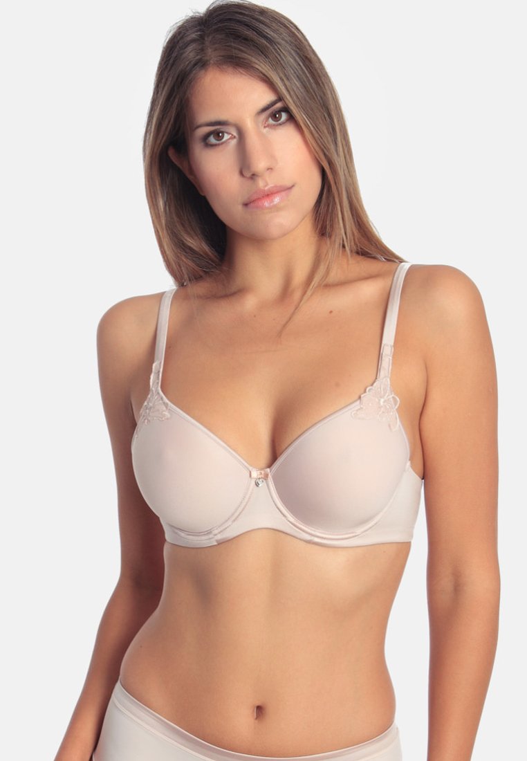Nude underwire bra with floral lace accents, smooth fabric, adjustable straps, and a decorative front clasp.