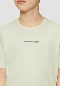 Lichtgele katoenen T-shirt met ronde hals. Voorzien van zwart bedrukte tekst aan de voorkant met zinnen over het verzamelen van momenten en limonade.