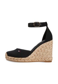 Μαύρο παπούτσι με σφήνα από καμβά, με λουράκι στον αστράγαλο και χρυσές λεπτομέρειες, που διαθέτει τακούνι τυλιγμένο με γιούτα και στρογγυλεμένη μύτη.