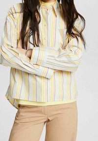 Randig skjorta med knäppning i ljusa färger (gul, pastellrosa, blå) med en avslappnad passform, som har en bröstficka och lång ärm.