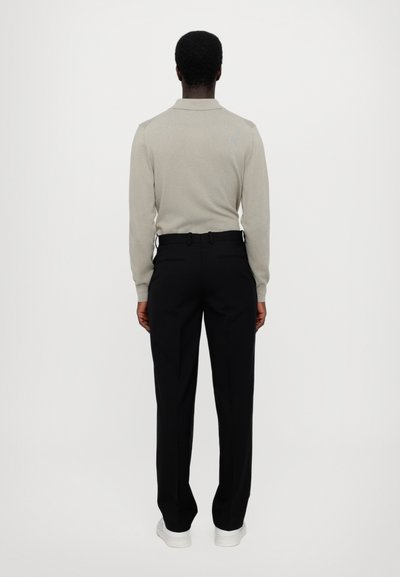 Hellgrauer, langärmeliger Polo-Pullover mit Kragen, kombiniert mit schwarzen, taillierten Hosen und weißen Sneakers. Minimalistisches Design, ohne Muster.