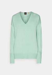 Pull vert clair à manches longues avec col en V, poignets et ourlet côtelés, présenté sur un fond blanc uni.