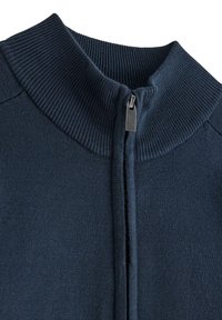 Marinblå stickad zip-up-tröja med hög ribbad krage och dragkedja framtill. Mjuk textur, med sömlösa sidor för en ren finish.