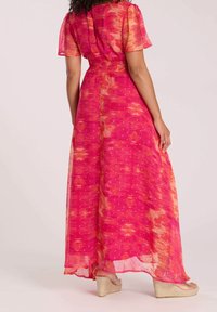 Maxi-jurk met korte mouwen in roze en oranje verloop. Heeft een geplooide taille en een gelaagd, vloeiend ontwerp met een subtiel stippenpatroon.