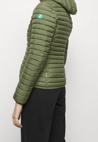 Doudoune verte avec un matelassage horizontal, capuche intégrée et un petit emblème bleu sur l'épaule. Présente une accentuation en menthe contrastante.