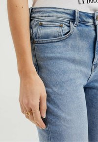 Světle modré džíny s úzkým střihem, s klasickým pětikapsovým designem, jemným efektem vymývání a zlatými detaily.