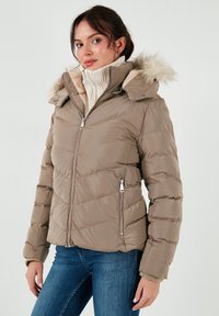 Giubbotto trapuntato in marrone chiaro con cappuccio rifinito in pelliccia sintetica, chiusura con zip, due tasche laterali e polsini a costine. Presenta un design trapuntato.
