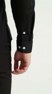 Chemise noire à manches longues avec des poignets boutonnés, présentant un tissu lisse et non texturé. Les boutons blancs contrastent avec le matériau noir.