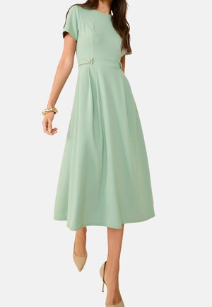 Mintgroene midi-jurk met korte mouwen, aangesloten lijfje, geplooide rok en gouden knoopdetail in de taille. Soepele textuur en vloeiende silhouet.