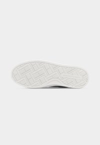 Λευκή εξωτερική σόλα από καουτσούκ με υφή γεωμετρικού πέλματος και ανάγλυφο λογότυπο "Tommy Hilfiger" κοντά στη φτέρνα.