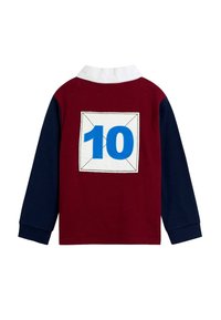 Hosszú ujjú rögbi póló, tengerészkék ujjakkal, burgundi testtel, fehér gallérral és nagy kék 10-es számmal egy fehér négyzetben a hátán.