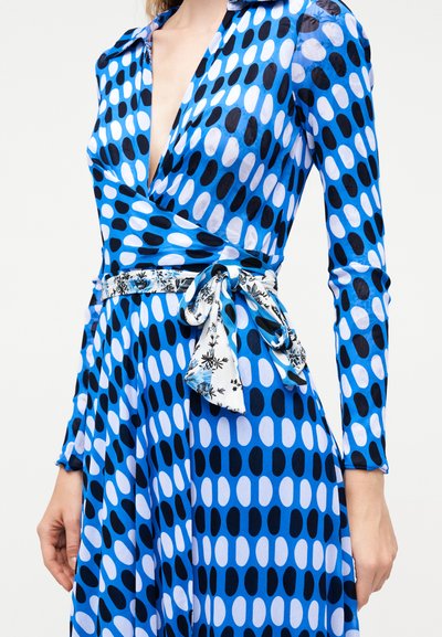 Μπλε φόρεμα τύπου wrap με μαύρα και λευκά οβάλ σχέδια, βαθύ V-λαιμόκοψη, μακριά μανίκια και δεμένη φλοράλ ζώνη στη μέση.