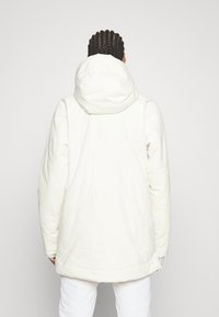 Weiße, gesteppte Jacke mit Kapuze, die eine glatte Textur und lange Ärmel hat, entworfen für Wärme und Komfort.