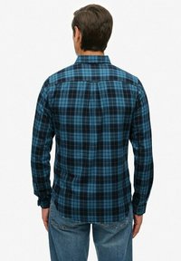 Blauwe en zwarte geruite shirt van een lichtgewicht stof met lange mouwen, rechte rug yoke en knoopmanchetten. Gecombineerd met lichte spijkerbroek.