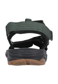 Bakre vy av svarta sandaler med gröna tygremmar, med en texturerad sula med bruna accenter, designade för komfort och stabilitet.