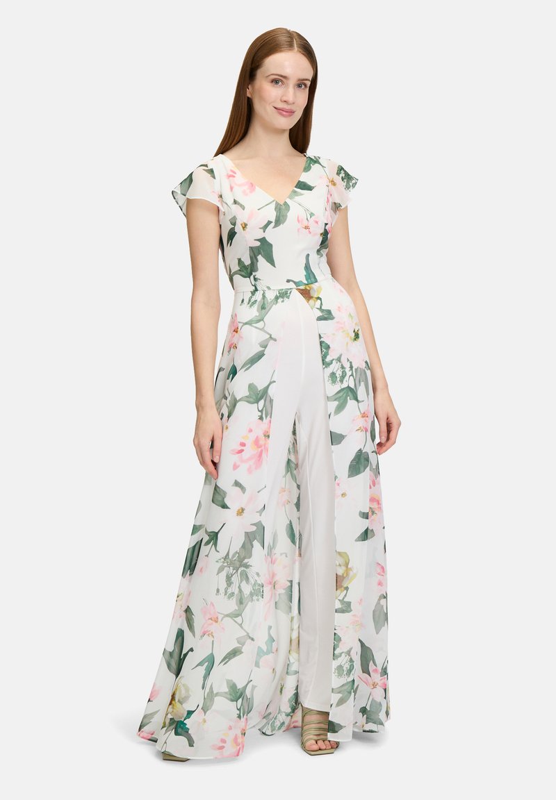 Kwiatowa sukienka maxi w kolorze białym, z krótkimi falbanami na rękawach, głębokim dekoltem w serek, bocznymi rozcięciami i warstwą przejrzystego materiału z różowymi i zielonymi wzorami.