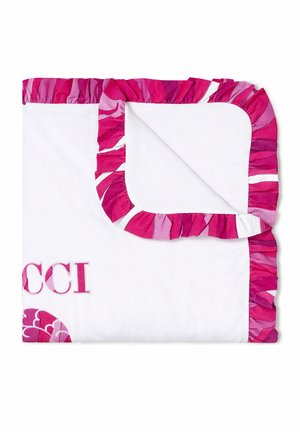 Couverture blanche avec bords froncés rose et violet, pliée pour montrer les coins, avec un texte brodé rose partiel et un motif floral.