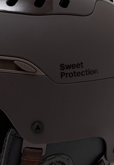 Pruun kiiver ventilatsiooniavadega, tekstureeritud pind ja must aksent. Omab "Sweet Protection" logo ja kinnituskruvi.