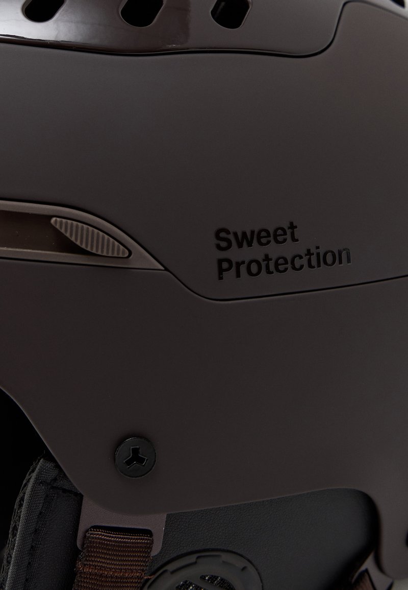 Brown helmet with vent holes, textured surface, and a black accent. Features "Sweet Protection" logo and a fastening screw.
