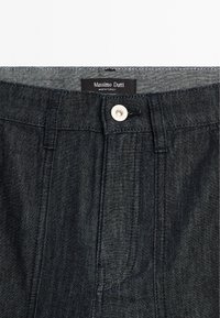 Tmavé džínové kalhoty s klasickým designem, viditelným šitím, knoflíkovým zapínáním a štítkem s nápisem "Massimo Dutti."
