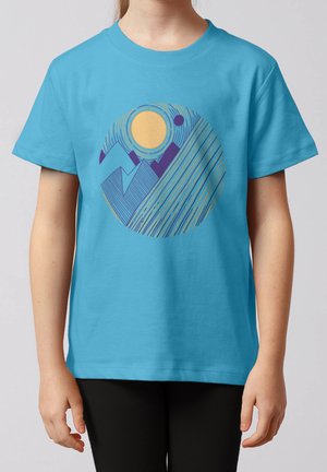Kind trägt blaues T-Shirt mit abstraktem kreisförmigem Berg- und Sonnenmotiv in Gelb, Blau und Lila auf der Vorderseite.