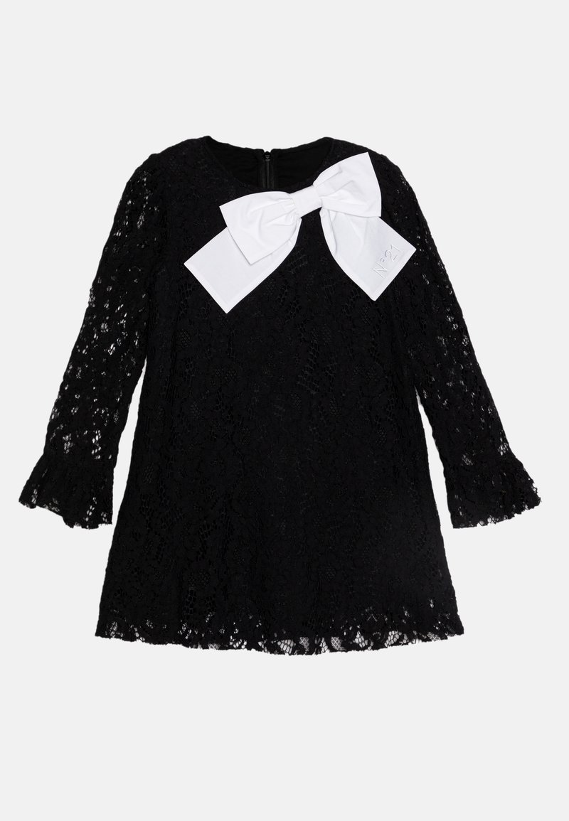 Robe en dentelle noire à manches longues, avec un ourlet festonné et un grand nœud blanc à l'avant. Elle possède une fermeture éclair au dos.