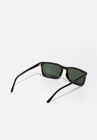 Ochelari de soare tortoiseshell cu lentile verzi. Rame pătrate, material plastic neted și acetate subțiri negre. Detaliu cu logo pe lateral.