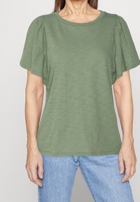 Lys grøn kortærmet T-shirt med en afslappet pasform og rund halsudskæring. Blødt, tekstureret stof med samlede detaljer ved skuldrene.