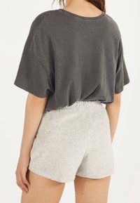 Koolgrijze oversized T-shirt met verlaagde schouders, gecombineerd met lichtgrijze heather shorts met een elastische tailleband. Zachte, casual stof.
