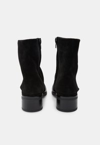 Črne antilopske gležnjarje z gladkim zaključkom, zadrgo na hrbtni strani in debelim črnim peto. Zgornji del je rahlo spušten brez vidne blagovne znamke.