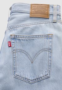 Lyseblå denim jeans baklomme med Levi's rødt merke og brun læretikett med Levi Strauss & Co.-merket på midjebåndet.