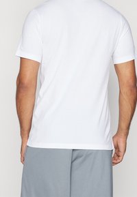 Bílý tričko s krátkým rukávem a kulatým výstřihem, vyrobené z měkké bavlny. Čistý střih, minimalistický design, žádné viditelné logo ani vzory.