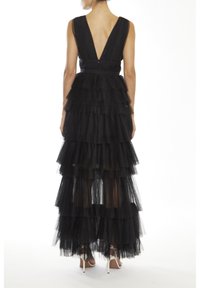 Zwarte tule jurk met een diepe V-rug, gelaagde ruffles en een strakke taille. Het ontwerp is lang en heeft een transparante overlay.