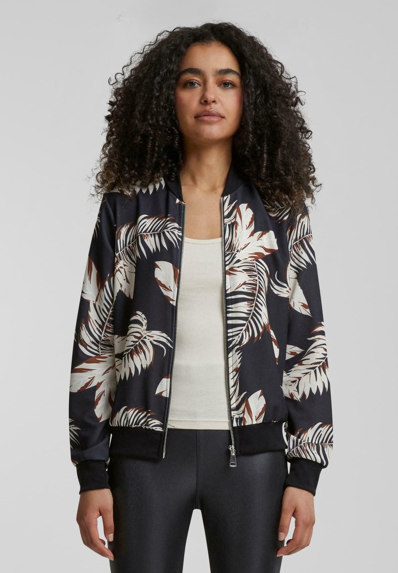 Veste bomber noire avec un grand motif de feuilles tropicales blanches et brunes. Tissu lisse avec une fermeture éclair et des poignets côtelés.